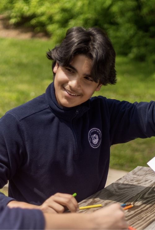 male student sitting at outdoor picnic table