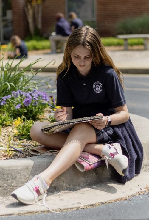 female student sitting outside sketching