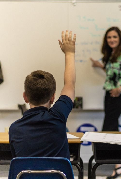 student in classroom raising hand