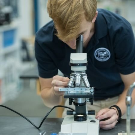 upper school student looking through microscope